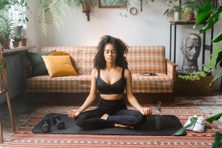 Femme méditant sur un tapis de yoga dans un intérieur calme