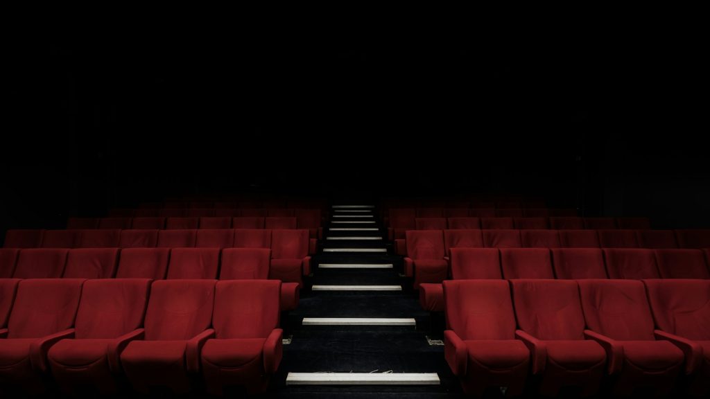 Rangées de fauteuils rouges dans une salle de cinéma sombre