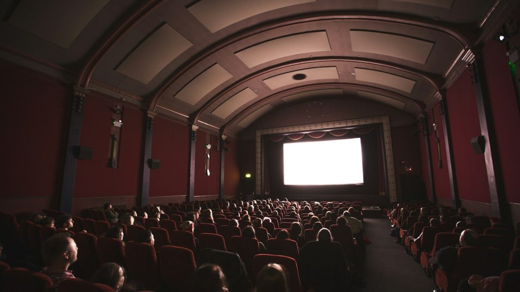 Public regardant un écran dans une salle de cinéma sombre