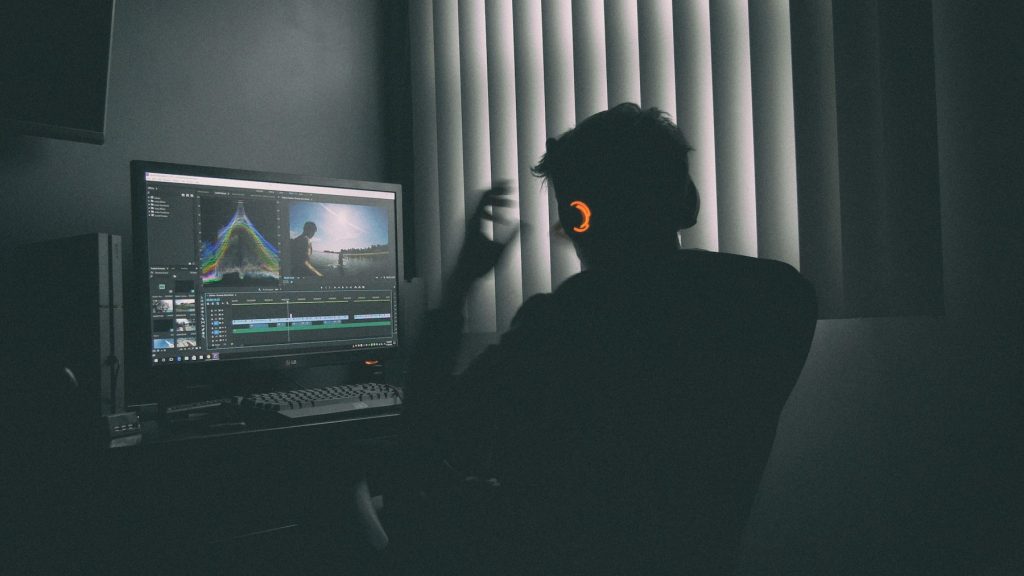 Personne réalisant un montage vidéo dans une pièce sombre